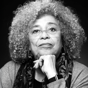 A black and white image of a brown skinned women with long gray curly hair.