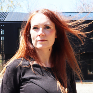 A woman with red hair looking past the camera