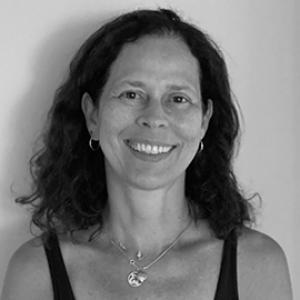 A woman with shoulder length hair wearing a black tank top and necklace.