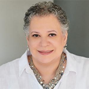 woman with short hair wearing a white shirt and necklaces