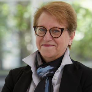 A woman with short red hair and glasses smiling