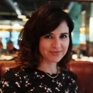 A person with brown medium length hair wearing a necklace