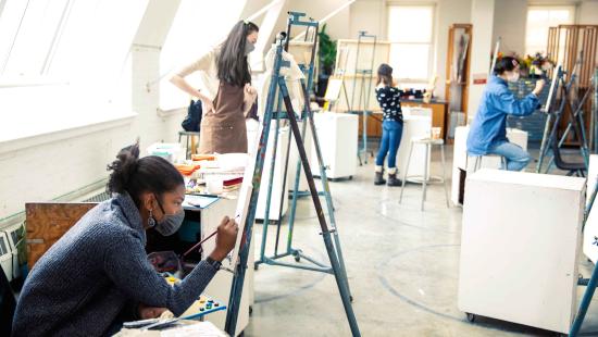 Four students in a painting studio at different easels.