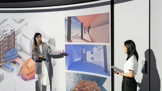 Two students presenting designs in front of a digital projection screen