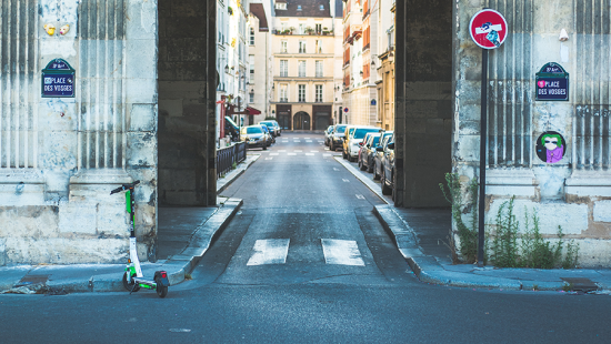 an archway into a city street with signs and cars.