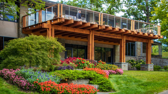 A balcony structure surrounded by bright green grass and colorful flowers.