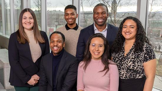 Six students gathered for a posed portrait in from of glass windows