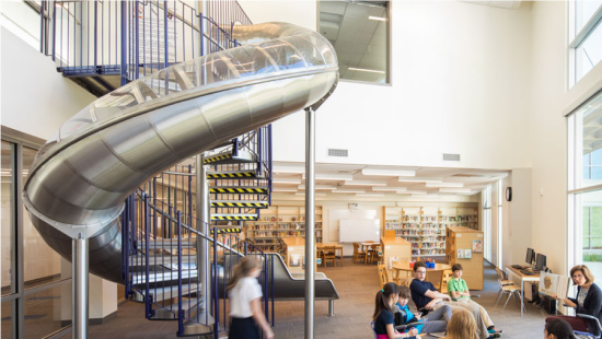A large metal slide with children sitting in front.