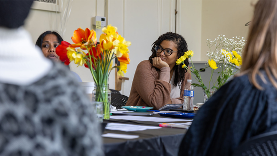 group of people gathered around a table for a meeting with bright flowers at the center