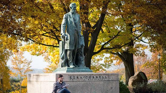 bronze statue of a man on a pedestal on a college campus