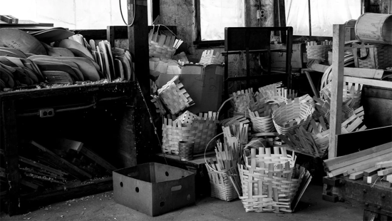 Pile of partially constructed baskets stacked on a concrete floor.