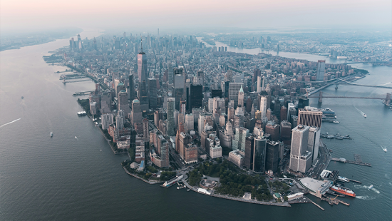 An aerial view of New York City surrounded by water with a hazy sky.