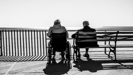 An elderly man and women sit neat the water side.