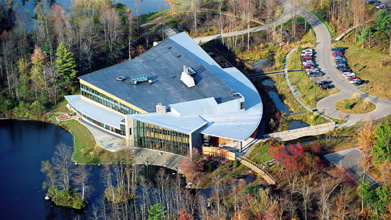 An aerial view of a building surround by lakes and trees.