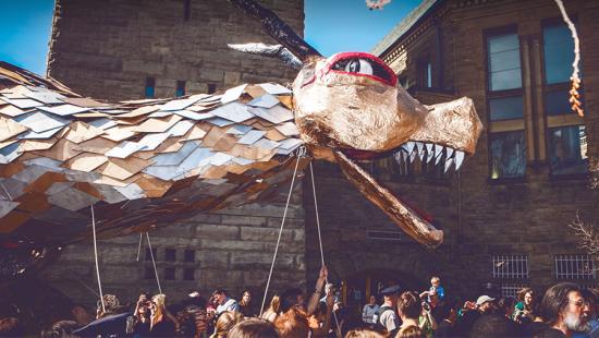 Enormous dragon puppet controlled by a crowd of students parades down the street