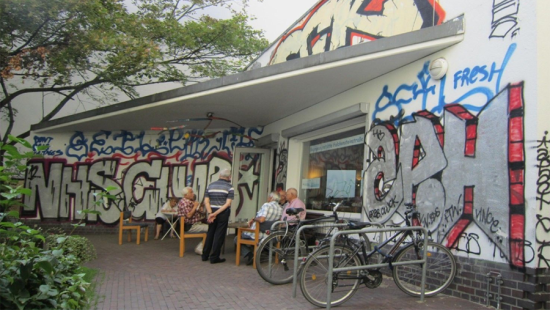 Group of people gathered in from of a graffiti tagged building