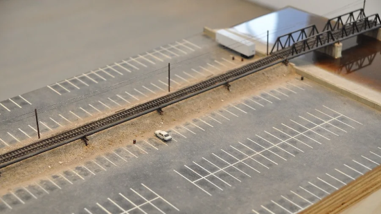 Model of a parking lot with train tracks running overhead.