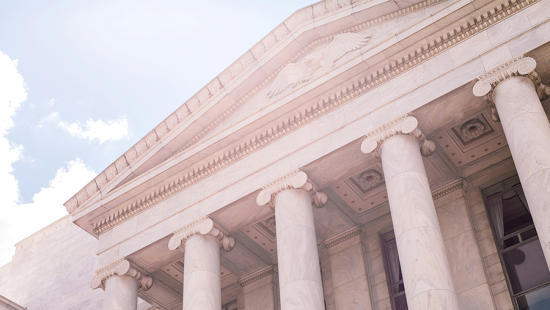 A white building with columns backed by blue sky.