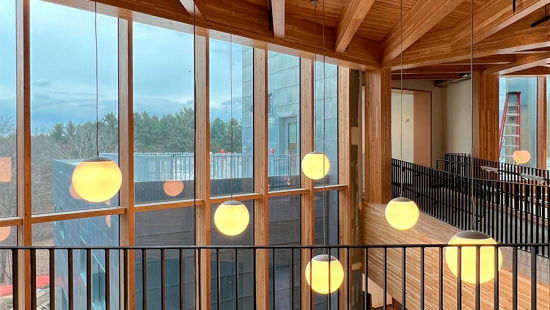 Yellow sphere lanterns hanging from the ceiling of a wooden room with large windows.