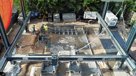 Aerial view of a 3D printer at work on constructing a concrete wall. 