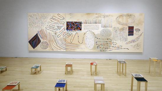 A large painting on a wall and ten small decorated tables.