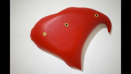 Curvy three-sided red cushion with three brass grommets.