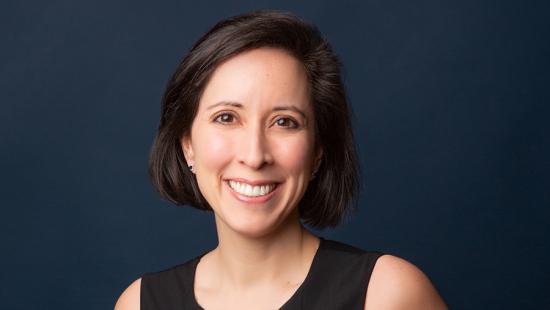 headshot of a woman with dark hair on a dark blue background in a black dress