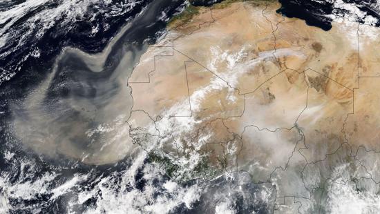 A satellite view from space of the African continent through clouds.