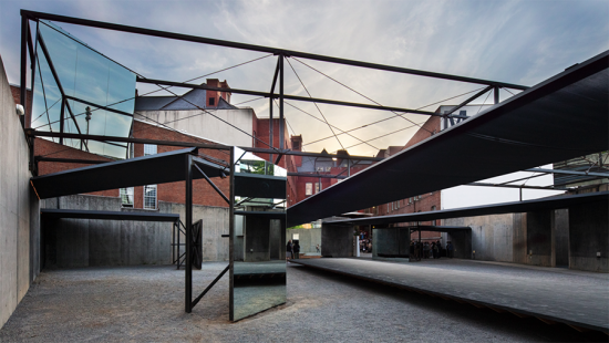 metal girders criss cross an outdoor space between low walls.