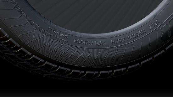 Sidewall of a black automobile tire on a black background.