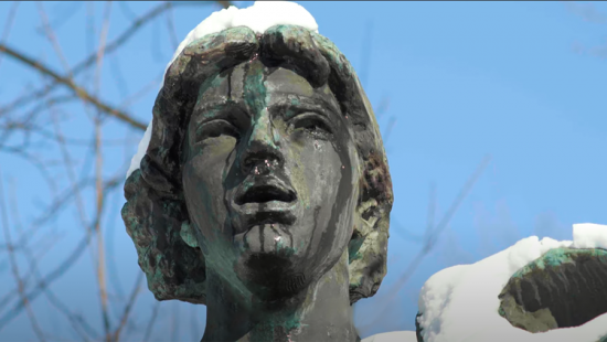 Statue of a person's face with snaow and blue sky.