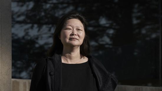 A person posing for a photo on a dark background.