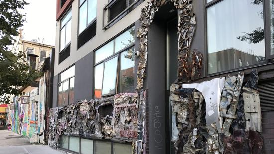 Storefront on a city street with a raised motif sculpture applied to it.