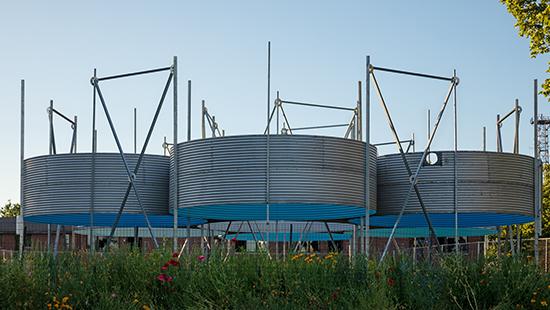 Six circular sections of corrugated metal grain silos grouped together in a field.