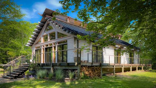 A wooden building with sloped roof on a raised deck, trees, and blue sky.