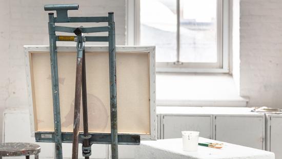 the back of a painting on an easel in a white room with a window