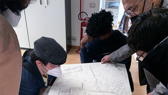 Four students and one teacher gathered around a map spread across a table