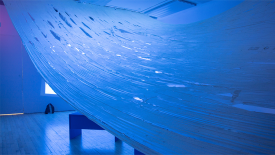 Large sheet of plastic hung across a room lit with blue tinted light