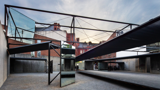 Mirrors placed in a concrete courtyard to reflect surroundings and overhead beams