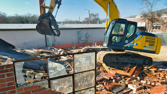 Demolition of a brick building with an excavator
