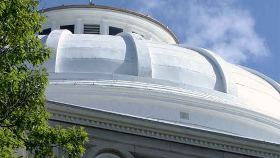 White building dome against a blue sky with cloud cover