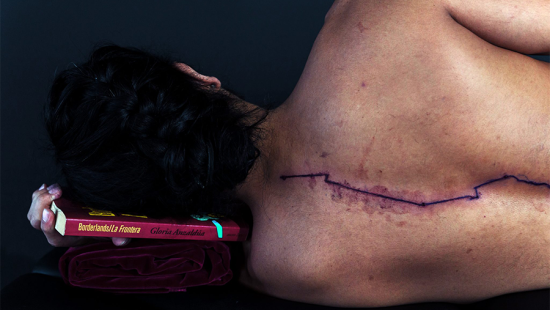 man laying on his side with back to the camera revealing a bleeding wound running down his spine