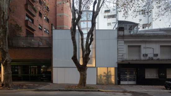 Exterior of contemporary white building on a residential street with tree planted in front.