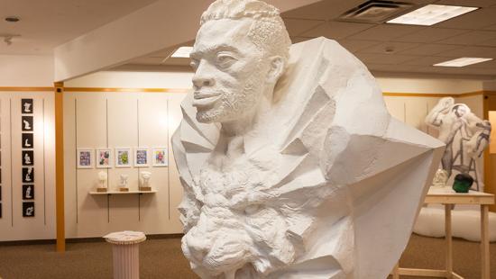 plaster bust of an African American man positioned above a cast of a roaring lion