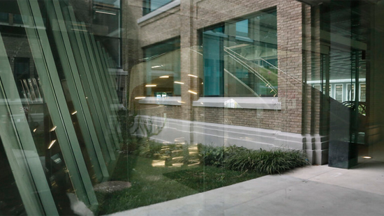 View of a brick building through a glass window with reflections