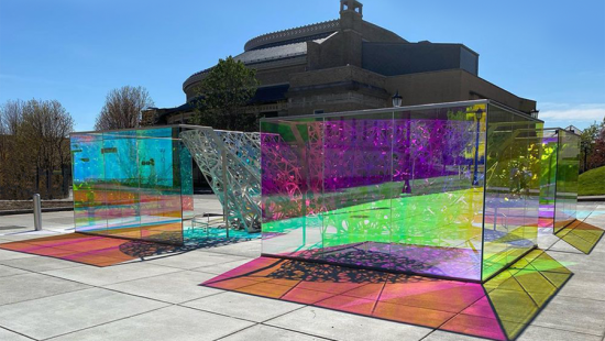 Multicolored glass boxes reflecting multicolored light onto concrete.