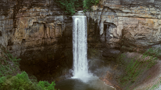 A waterfall in a valley surrounded by trees.