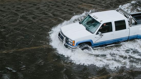 Pickup truck driving through flooded road