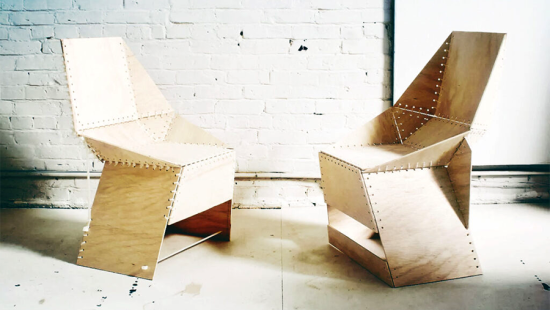 Two chairs, turned toward one another, built out of plywood panels laced together 
