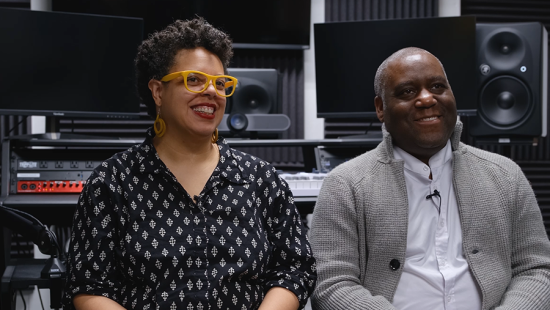 two people seated in front of recording studio equipment